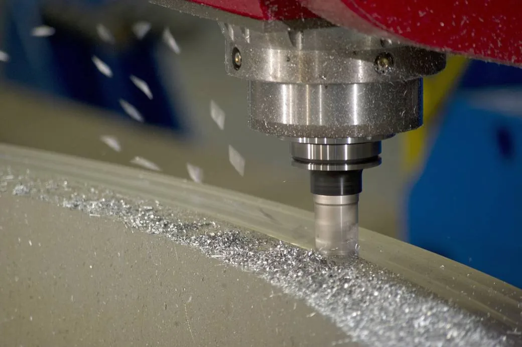 An end mill cuts into a metal ring, leaving a trail of aluminum chips.