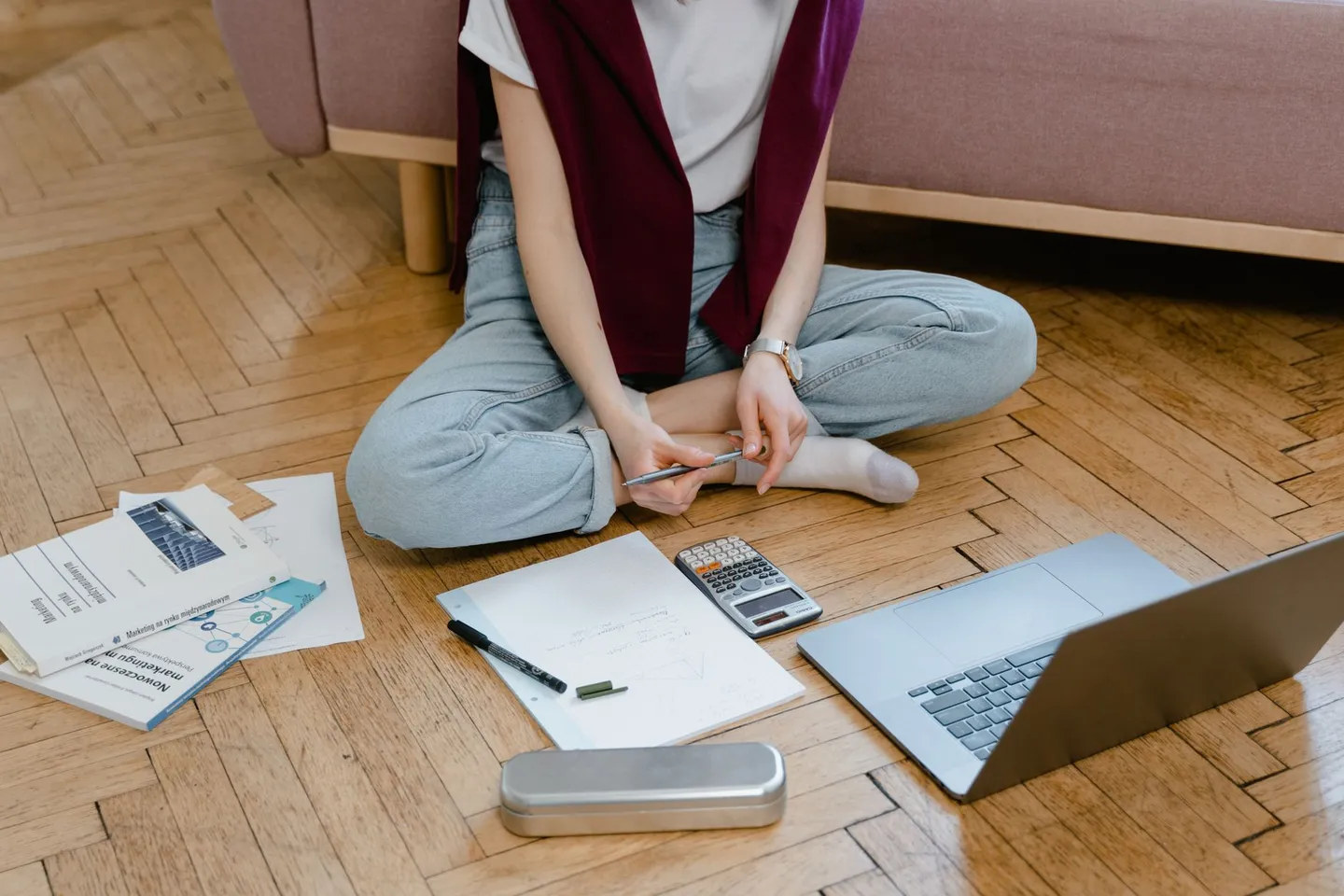 Student studying at home on the floor with a laptop, scientific calculator and handwritten graph-paper notes
